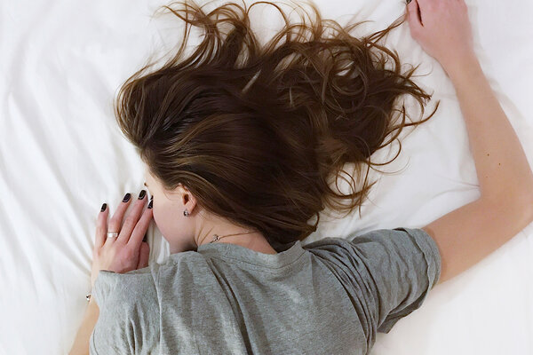 Frau schläft auf Bett.