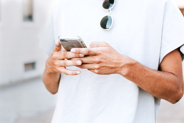 Mann mit Sonnenbrille hält iPhone X