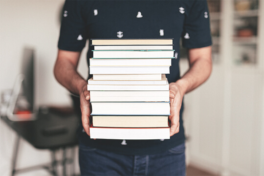 Mann trägt einen Stapel Bücher