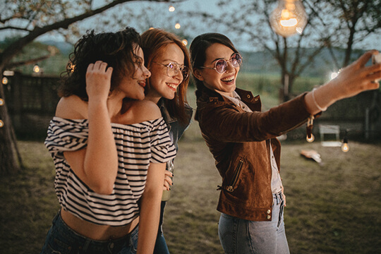 Drei Frauen machen ein Selfie mit einem Handy.