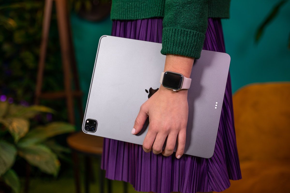 Person mit refurbished Apple Smartwatch am Handgelenk, hält wiederaufbereitetes iPad in der Hand.